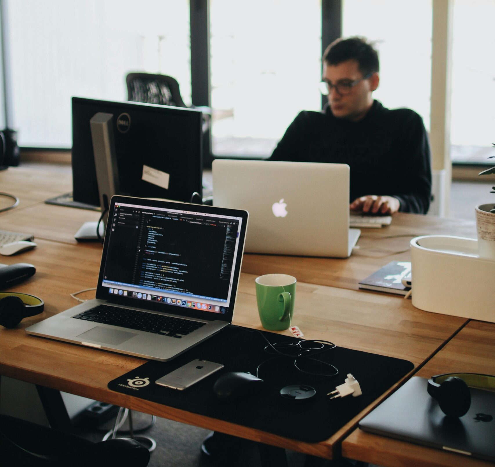 A web developer working on code in a modern office setting with multiple devices.